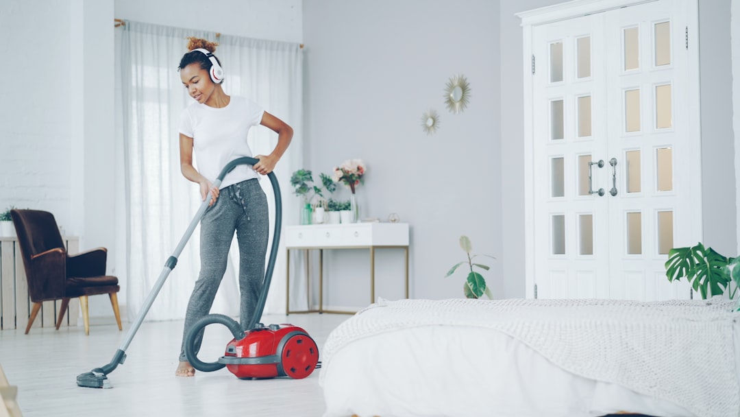 services-02 Creative African American teenager is hoovering floor in nice apartment, listening to music with headphones, dancing and singing. Electrical appliances, clean-up and fun concept.