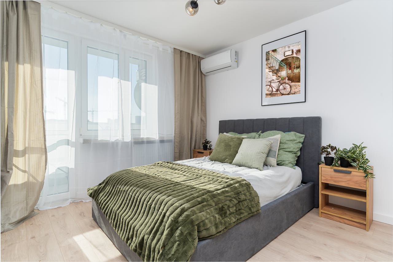 why-choose-us A stylish bedroom with green accents, natural light, and decorative plants.